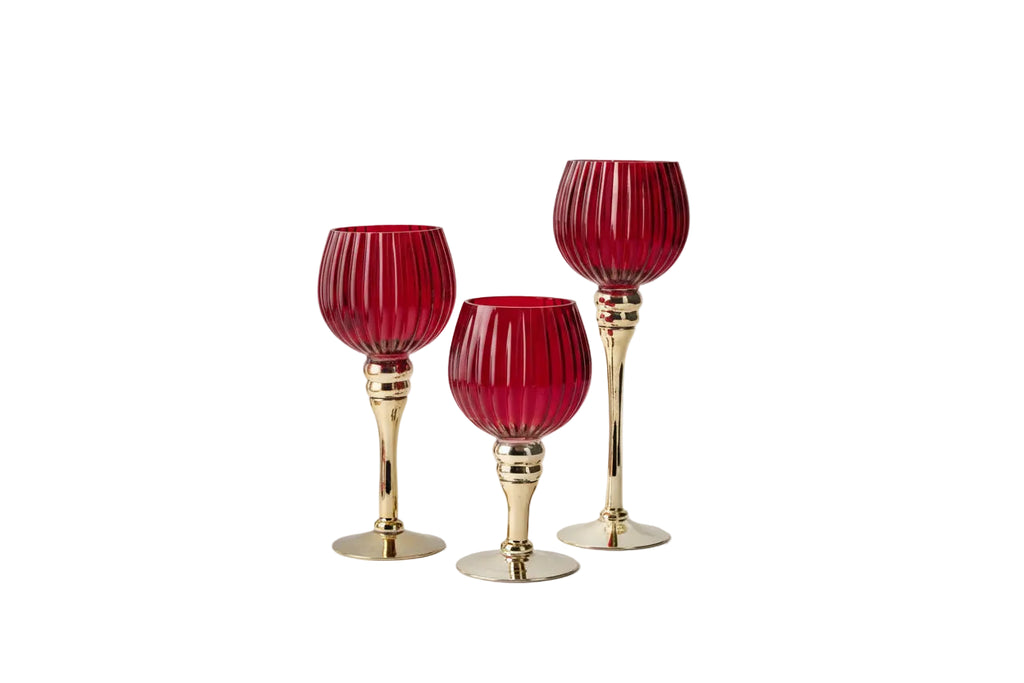 Three red glass goblets with gold bases on a white background