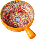 Decorative bowl with intricate patterns and an orange handle on a white background