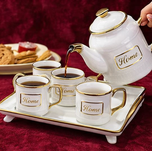 Ceramic tea set with 'Home' branding on a red surface