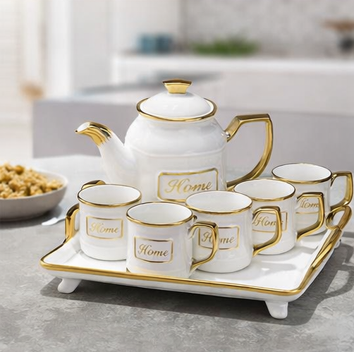 White ceramic tea set with gold accents on a tray, featuring the word 'Home'.