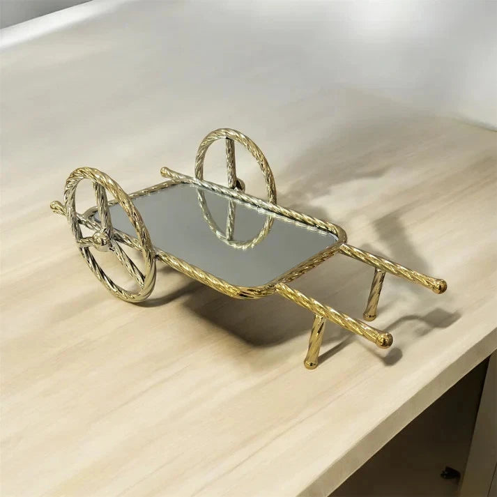 Gold decorative wheelbarrow on a light wooden surface
